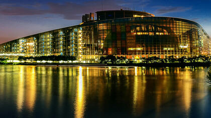 The European Union Parliament in Strasbourg, France, illuminated at night beside a body of water