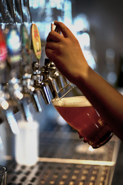 A man pours beer by hand in a craft brewery, illustrating the brewing process
