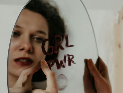 A girl stares at her reflection on a scribbled mirror