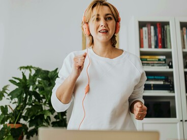 Listening to music through headphones, a woman exercises at home and engages in language learning at the same time
