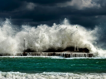 Big waves rolling beneath a cloudy sky, illustrating a tsunami triggered by an earthquake