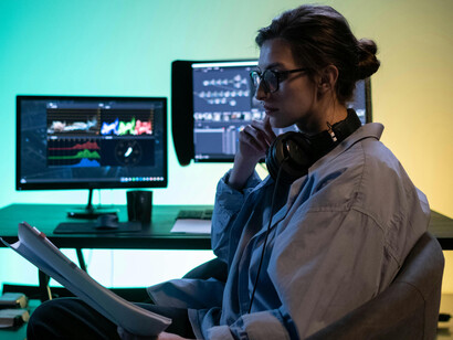 Woman sitting on chair working on multiple computer screens, symbolizing digital overload, information overload, and technology multitasking with a split-screen focus
