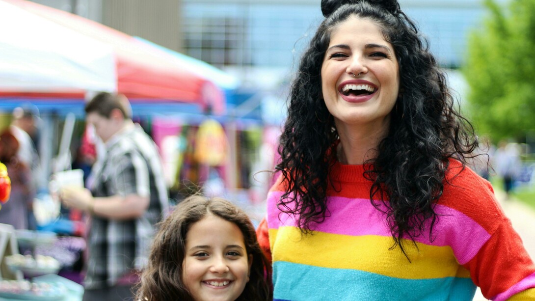 A woman in a rainbow sweatshirt with her child, symbolizing a queer family