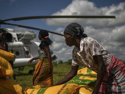 Local women assist in unloading humanitarian aid from a World Food Programme helicopter in Bebedo, Mozambique, on April 8, 2019, as part of relief efforts following Cyclone Idai