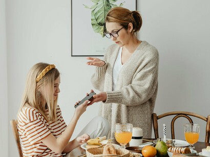 Mãe repreende filha por conta do uso excessivo do celular. Celulares, tablets, computadores – esses dispositivos, onipresentes em nossas vidas, tornaram-se o primeiro contato de muitas crianças com a palavra. A ponta dos dedos que antes traçava letras no papel agora desliza sobre superfícies luminosas, teclando e clicando