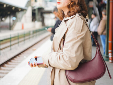 A woman stands alone on a train station platform, anticipating her next journey
