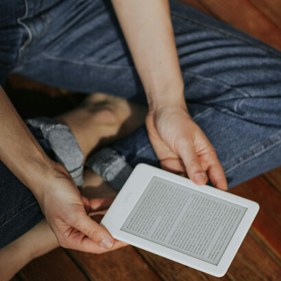 A person enjoys reading an e-book on a peaceful wooden deck