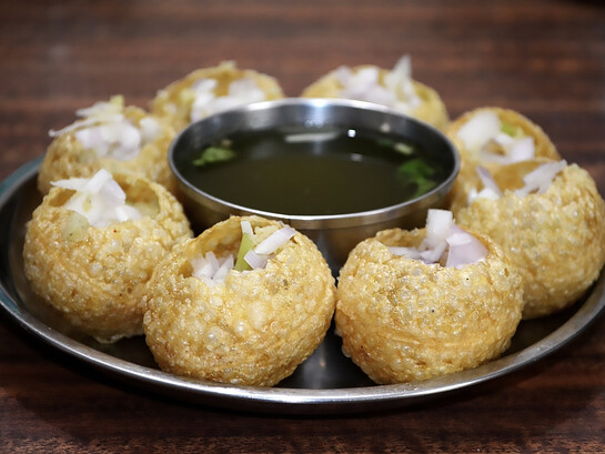 Panipuri—also known as golgappa, gappa, fuchka, phuchka, phuska, puska, batashe, padake, fulki, pakodi, or jalpooree—is a deep-fried, hollow, and crispy spherical shell, about 1 inch (25 mm) in diameter, traditionally filled with a mixture of potatoes, raw onions, chickpeas, and spices