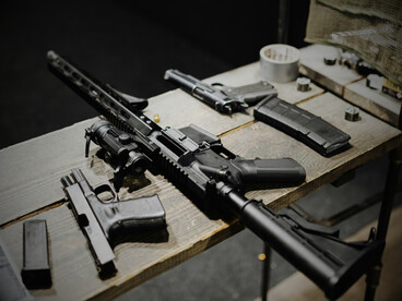 A set of guns resting on a table, symbolizing the main instruments behind the vague political promises of peace
