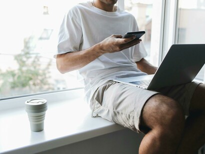 Gen Z man multitasking with laptop and phone