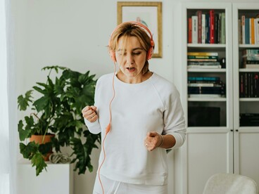 At home, a woman trains with headphones on, turning her workout into a dual session of fitness and language learning