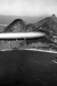 Dirigível LZ 127 "Graf Zeppelin" sobre o Rio de Janeiro. Estávamos todos juntos, minha mãe, meu pai, meus irmãos. Meus pais tinham me dado a permissão rara de andar um pouco mais longe, mas eu sabia que não podia ir muito além da barraca da pipoca. Ainda assim, minha curiosidade me empurrava, como sempre fazia