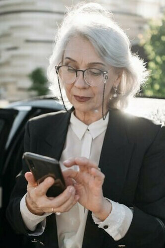 An elderly woman reading a newspaper on the street, reflecting French media culture