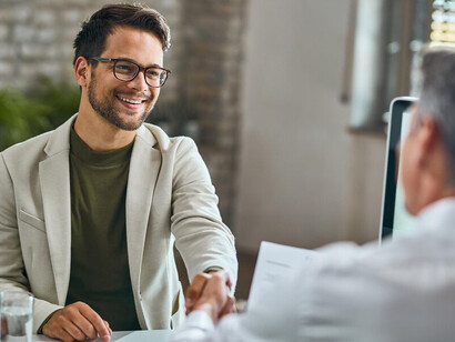 A confident male job candidate shaking hands with a human resources team member during a job interview in the office, showcasing the employer-candidate relationship