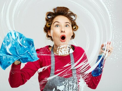 A young woman washes windows as part of her spring cleaning routine, using cleaning supplies to declutter and organize her home