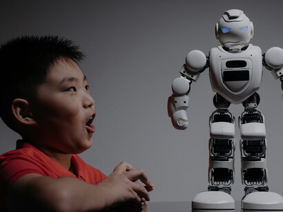 A boy gazes curiously at a white toy robot