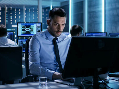 Close-up of a technical engineer working on a computer with multiple live-monitoring screens, illustrating generative AI