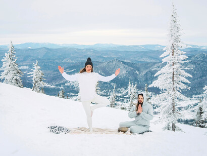 A couple practicing yoga in the winter mountains, showing how movement keeps the body warm and immunity strong
