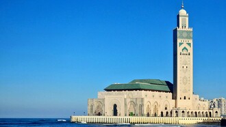 Morocco's Hassan II Mosque, set against a blue sky, representing the country's dedication to preserving its traditional architecture and design