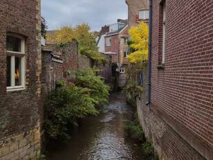 Along the river in Maastricht, a brown brick building rises among rows of houses and traditional Dutch architecture
