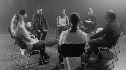 Grayscale photo of people sitting on chairs during a group therapy session