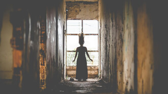 A woman standing behind the ruins of a torn-down castle, creating a spooky thriller atmosphere