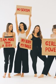 Mulheres de calças pretas segurando cartazes sobre o empoderamento feminino