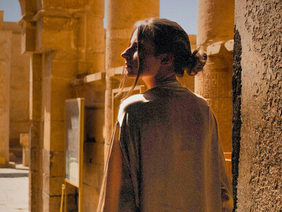 Une femme en manteau beige au temple de Louxor, Louxor, Égypte