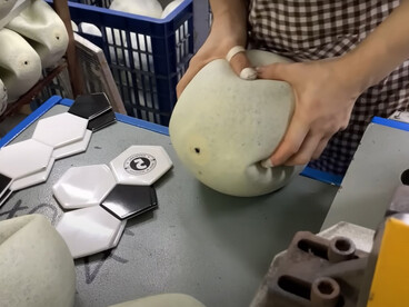 A woman is actively involved in the football manufacturing process