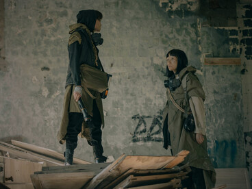 A man and a woman standing amid the remnants of a ruined world, representing the determination to endure even in the harshest realities