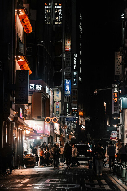 Nighttime scene in Tokyo, Japan, with people strolling between tall buildings illuminated by vibrant street signs