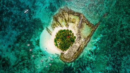 An aerial view of Guyam Island in Siargao, signifying the timeless allure of small islands surrounded by vast seas