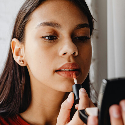 A young woman adds the final touch to her look, applying lipstick with care