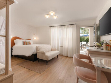 The room features a large bed with crisp white bedding and an arched, warm terracotta-colored headboard