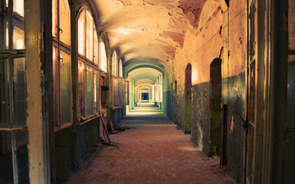 A deserted indoor hallway in a ruined, deteriorating house