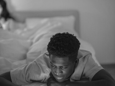 A couple in bed absorbed in their phones, showing how digital distractions create emotional distance and loneliness