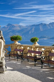 A statue sits on a bench overlooking Lake Como at Villa del Balbianello in Italy