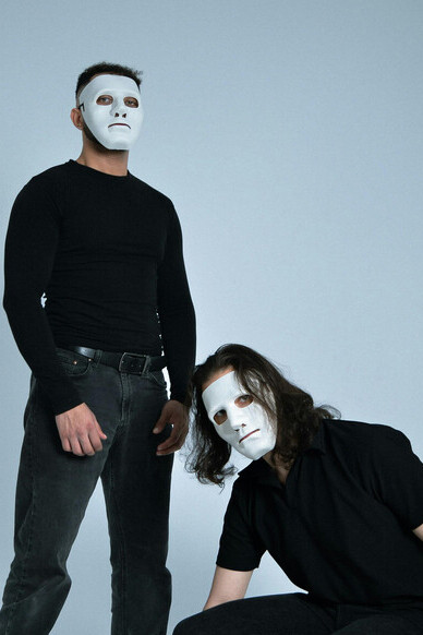 Two figures in white masks within a minimalist setting, symbolizing hidden identities and unspoken truths