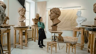 A sculptor works in his art studio, surrounded by tools and unfinished pieces