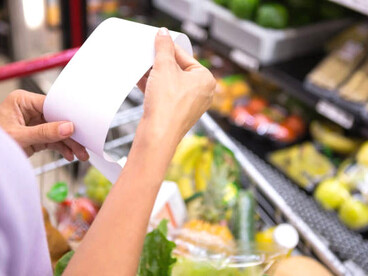 Woman shopping in a convenience store and checking her receipt, reflecting rising prices and inflation