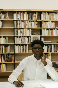 A male architecture student sitting at a table in the library, focused on his studies