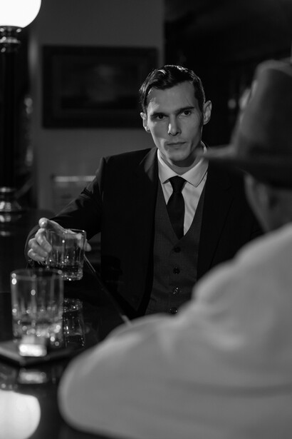 A monochrome photograph showing several men seated at a bar counter