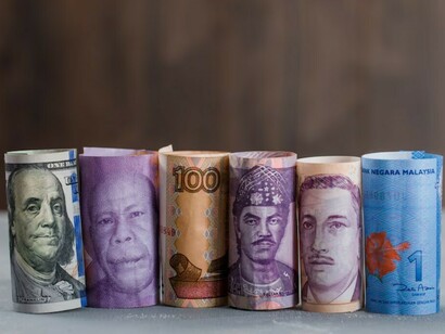 Different currency bills laid out on a table with a plaster and wooden surface