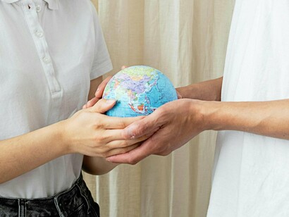 Two hands hold the Earth, reminding us that our future depends on shared responsibility, not division