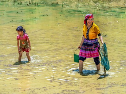 Família cigana lava seus pertences em rio. Mas conseguimos sentir os espaços? Trocamos energia com a casa, o bairro, a cidade, o país que escolhemos viver? Captamos as suas mensagens? Será este tecido um condutor de memórias?  Para os povos originários, a Terra é um ser vivo, com memória e sentimentos. Ela é um corpo ancestral, sábio, uma grande biblioteca onde consultamos os caminhos já trilhados, com rotas nem sempre ideais, cheia de erros que insistem em repetir-se