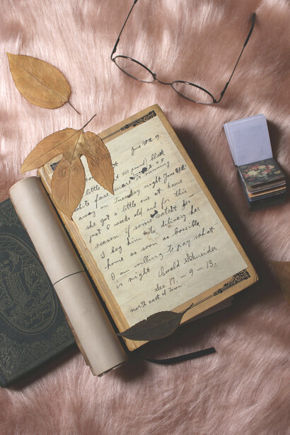 A vintage flat lay featuring an old diary with yellowed pages and pressed flowers, beautifully arranged on a rustic table