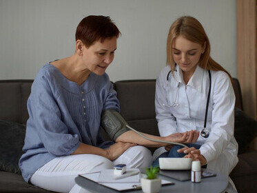 A smiling female doctor examining an elderly patient with a chronic illness, reflecting on the philosophy of illness, existential experiences, and medical ethics