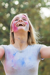 Happy woman enjoying a playful moment with powdered color, celebrating the joy of life and the connection between happiness and physical well-being