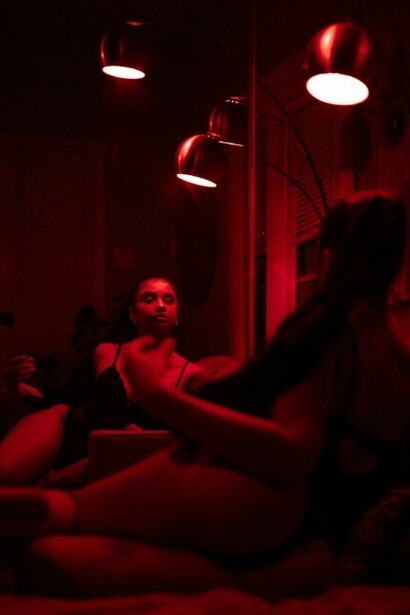 A woman in lingerie standing in a dimly lit room with dark red lighting