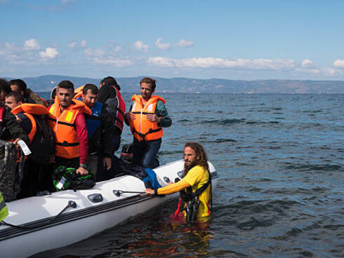 A migrant boat landing on the shores of Lesbos, Greece—symbolizing the broader migration crisis, border control challenges, and the realities of international migration